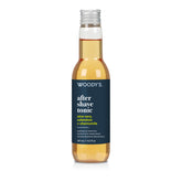 A 127 mL bottle of Woody's After Shave Tonic with a dark navy blue label and a silver cap, containing a golden-amber liquid, shown on a white background.