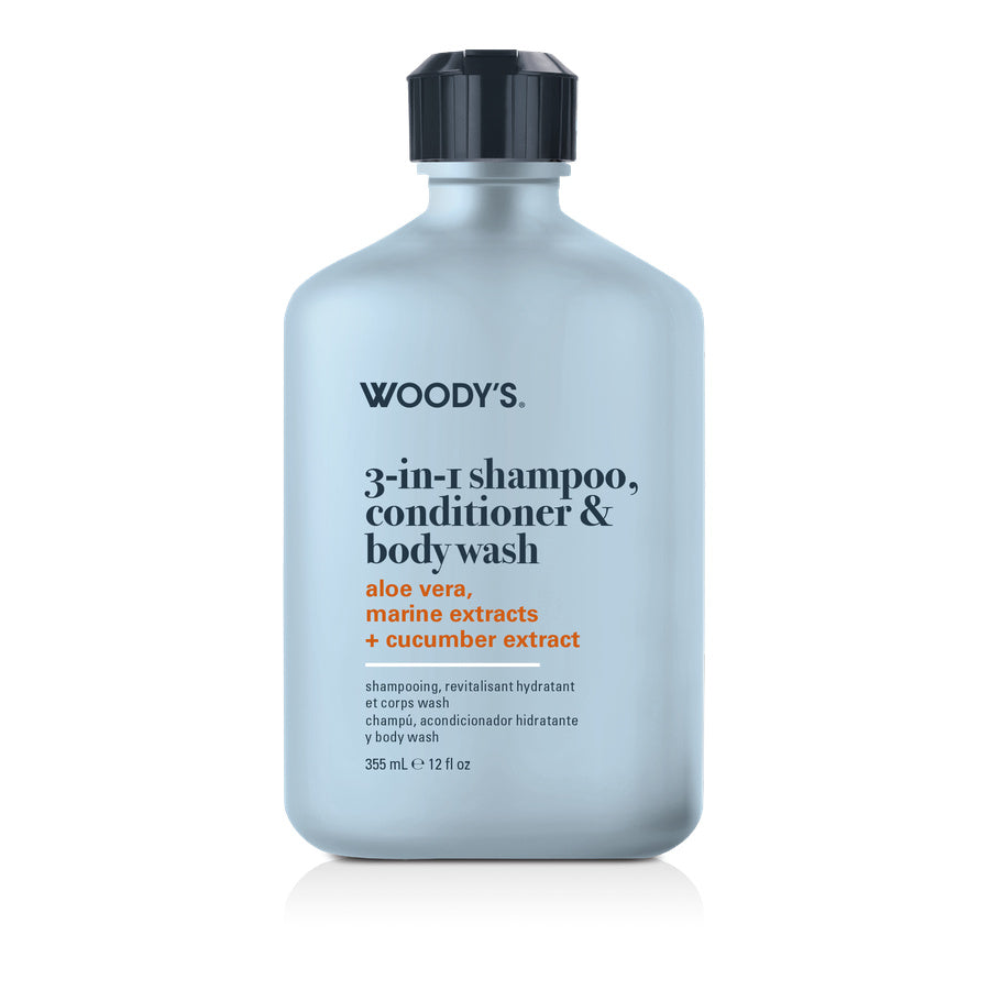 A bottle of Woody's 3-in-1 shampoo, conditioner, and body wash with a light blue-gray body, black cap, and black text on a white background.