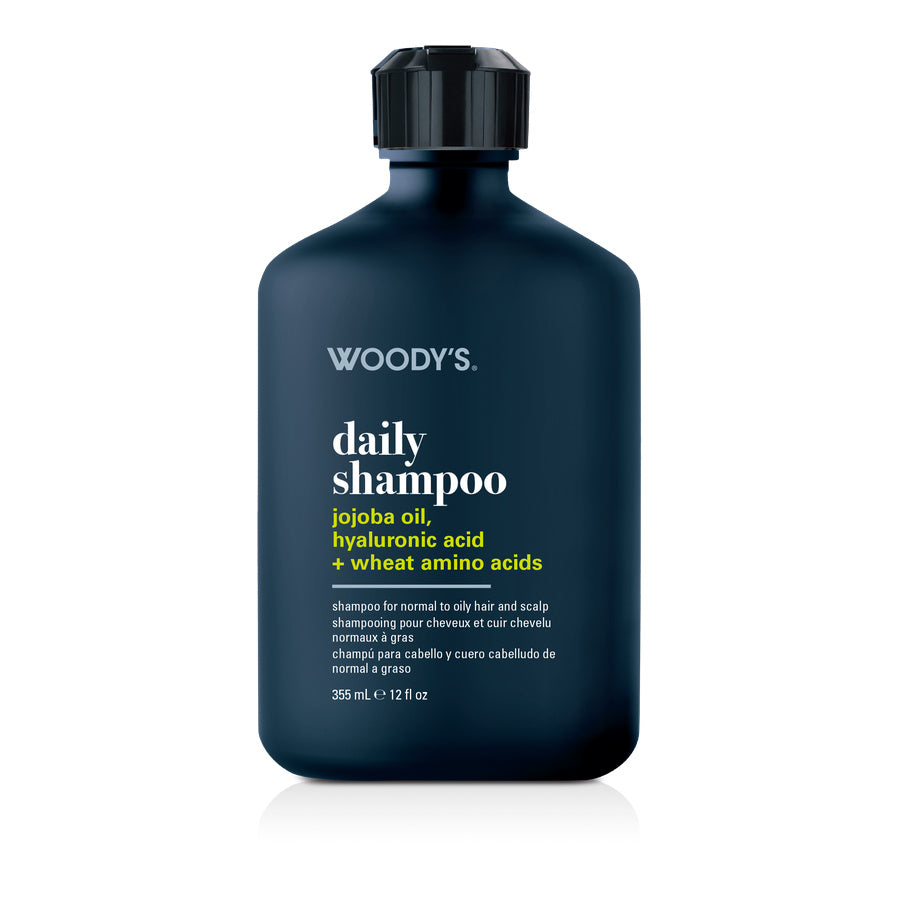 Woody's Daily Shampoo in a dark navy blue bottle with a black cap, on a white background with a soft reflection.