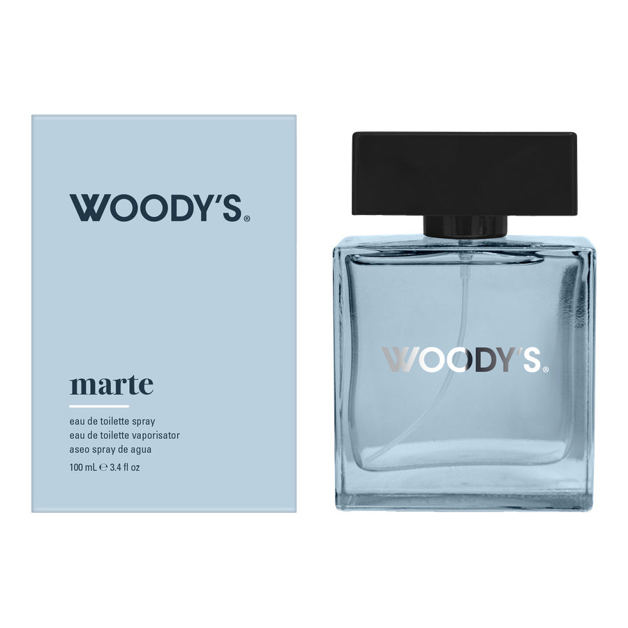 Woody's Marte Eau de Toilette bottle and packaging box. The bottle is made of clear glass with a light blue tint and a black cap, while the box is a pale blue with black text.