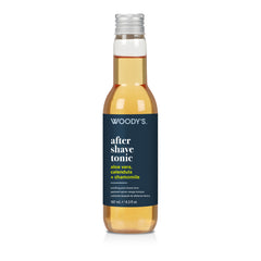 A 127 mL bottle of Woody's After Shave Tonic with a dark navy blue label and a silver cap, containing a golden-amber liquid, shown on a white background.