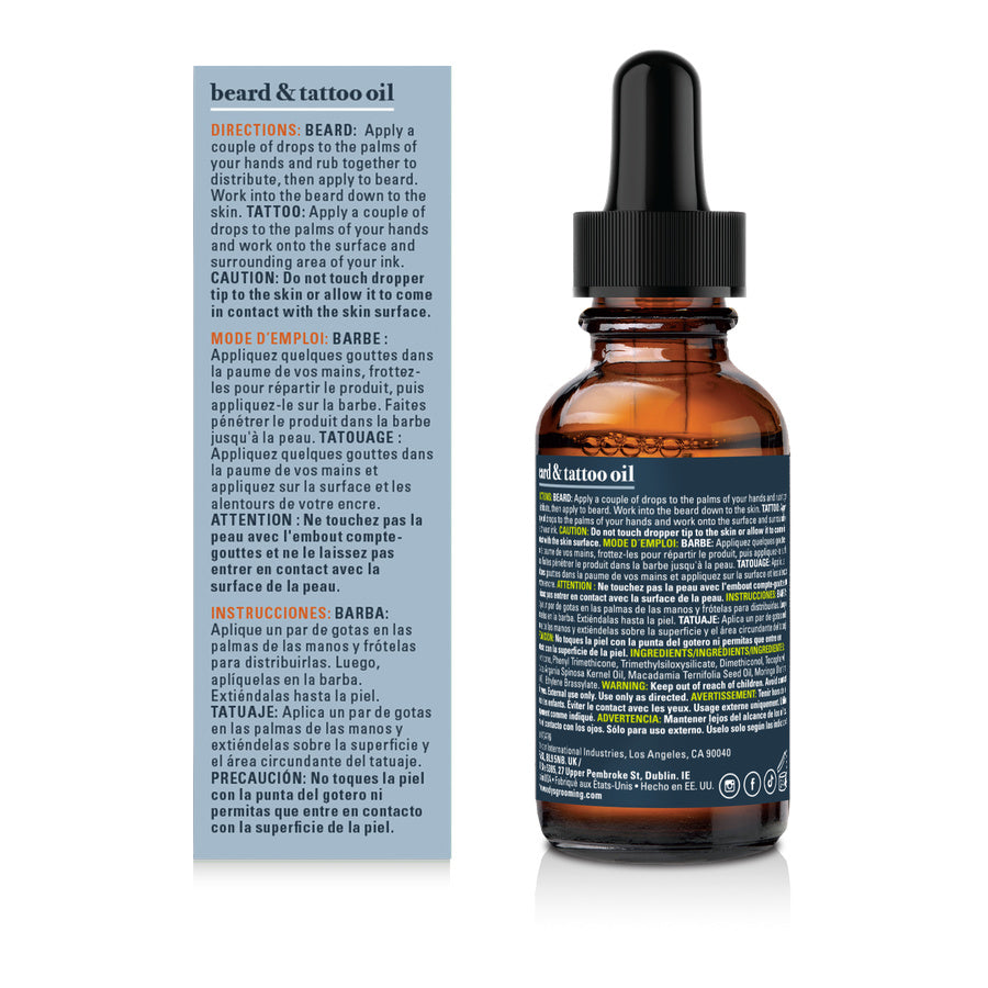 A bottle of beard and tattoo oil with a black dropper cap and amber glass bottle, shown next to its blue and white instruction card on a white background.