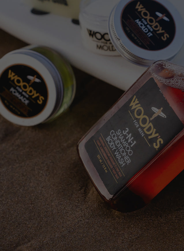 Woody's grooming products including a bottle and jars on a textured surface.